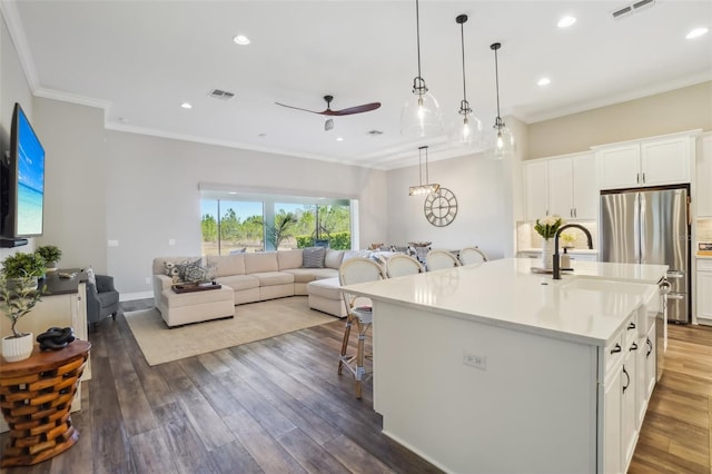 kitchen featuring open floor plan, a ceiling fan, visible vents, and a breakfast bar area