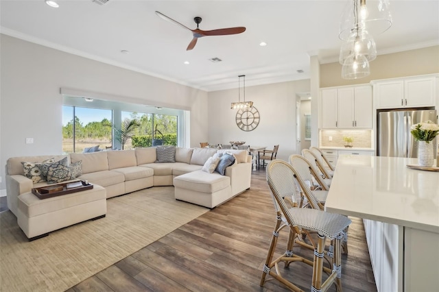 living room with recessed lighting, wood finished floors, visible vents, crown molding, and ceiling fan