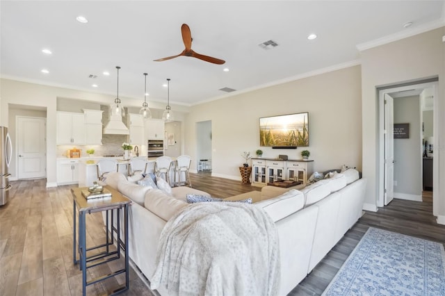 living room featuring recessed lighting, wood finished floors, visible vents, a ceiling fan, and baseboards