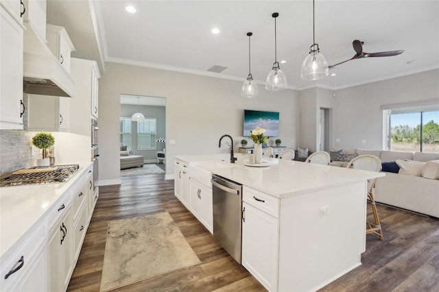 kitchen featuring recessed lighting, ornamental molding, appliances with stainless steel finishes, a breakfast bar area, and premium range hood