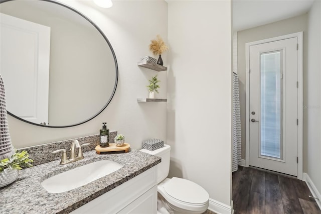 bathroom featuring baseboards, wood finished floors, toilet, and vanity