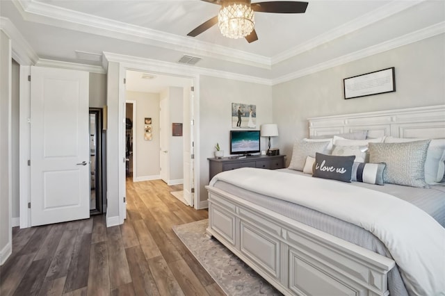 bedroom featuring a tray ceiling, baseboards, visible vents, wood finished floors, and ornamental molding
