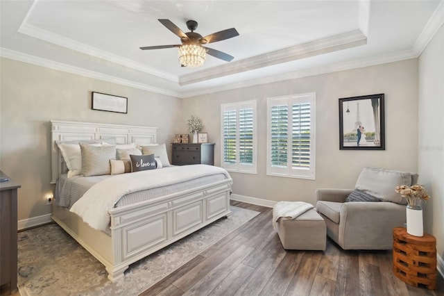 bedroom featuring a raised ceiling, wood finished floors, crown molding, and baseboards
