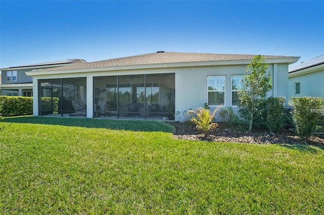 rear view of house with stucco siding, a sunroom, and a yard