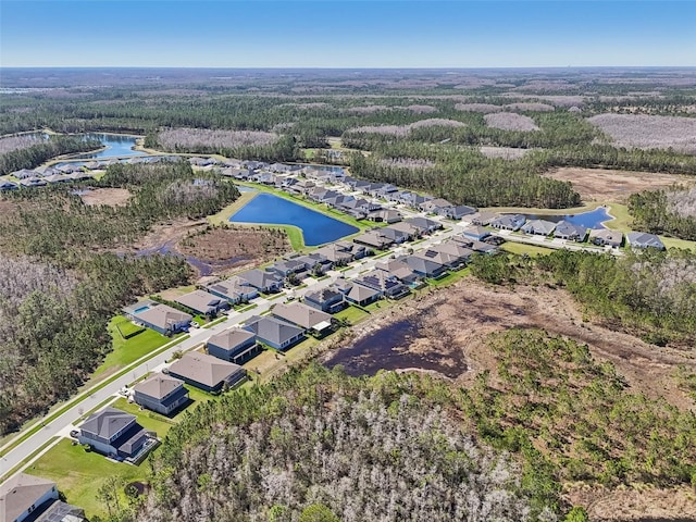 drone / aerial view featuring a view of trees, a water view, and a residential view