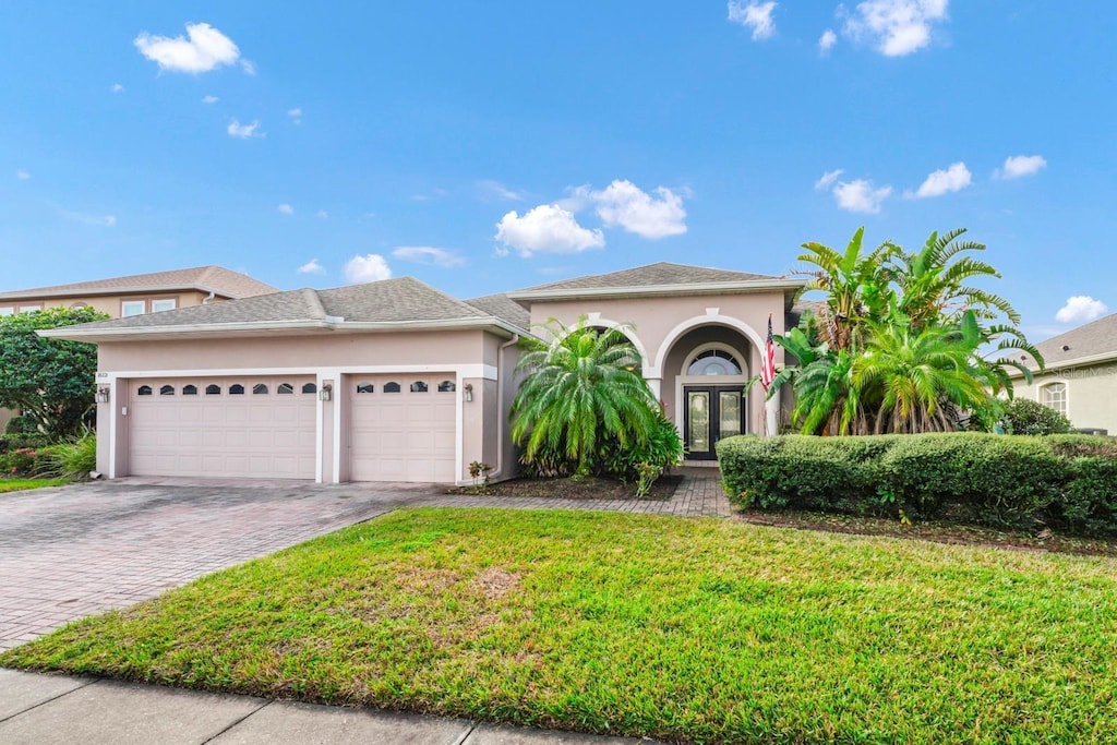 view of front of property with a garage, french doors, and a front lawn