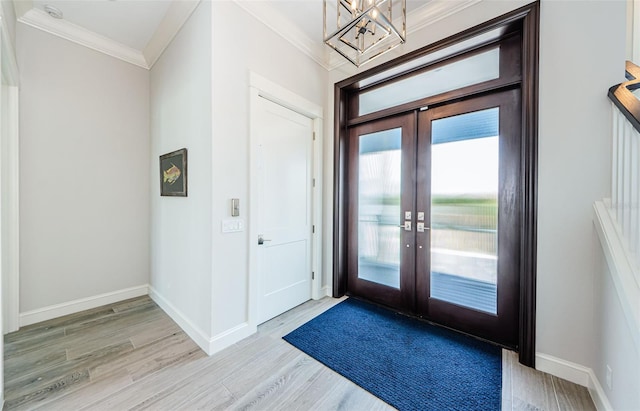 foyer entrance with ornamental molding, french doors, and light hardwood / wood-style flooring