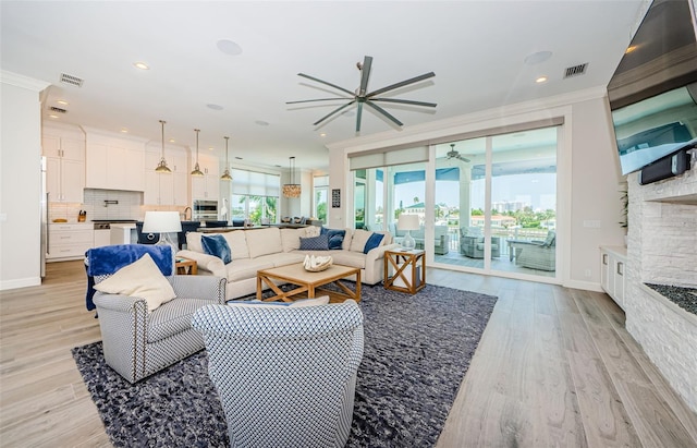 living room with ceiling fan, ornamental molding, and light hardwood / wood-style floors