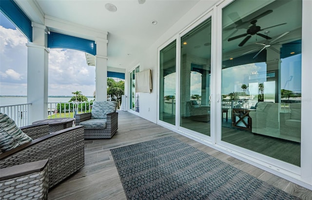 wooden terrace with a water view and ceiling fan