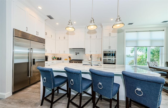 kitchen featuring sink, stainless steel appliances, white cabinetry, and hanging light fixtures