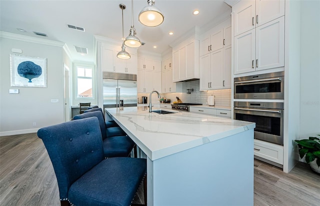 kitchen with sink, white cabinets, stainless steel appliances, and decorative light fixtures