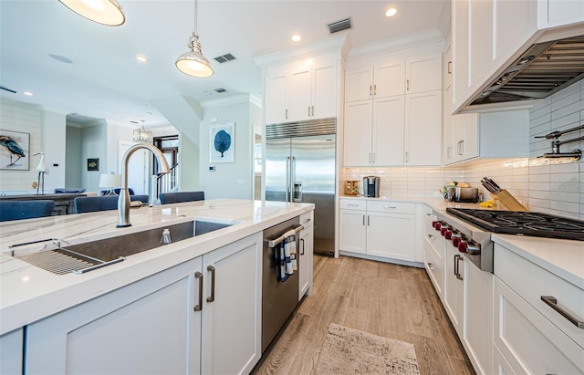 kitchen with white cabinets, hanging light fixtures, stainless steel appliances, and custom range hood