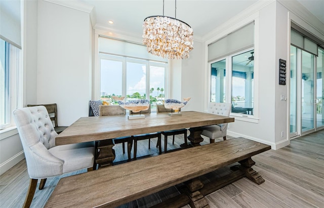 dining room featuring ceiling fan with notable chandelier, light hardwood / wood-style flooring, and ornamental molding