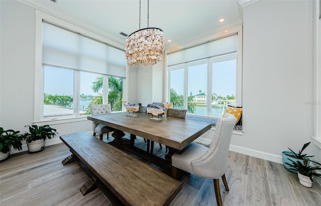 dining room with a water view, an inviting chandelier, and light hardwood / wood-style flooring