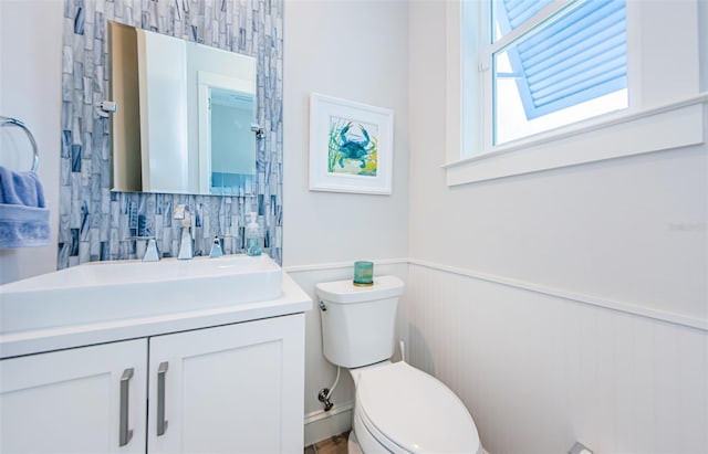 bathroom with vanity, toilet, and decorative backsplash