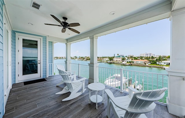 wooden deck with a water view and ceiling fan