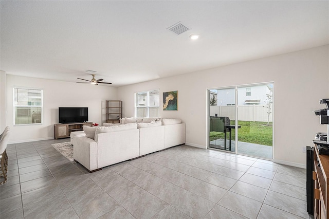 living area featuring light tile patterned floors, ceiling fan, a wealth of natural light, and visible vents