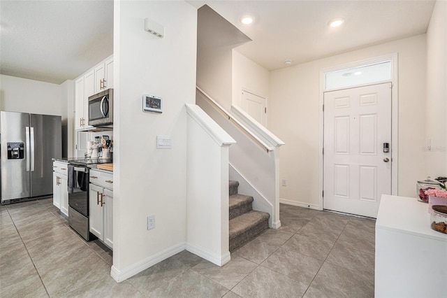 kitchen featuring light tile patterned floors, white cabinetry, baseboards, light countertops, and appliances with stainless steel finishes