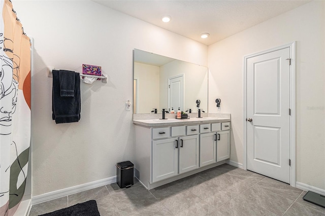 full bath with a shower with shower curtain, a sink, baseboards, and double vanity