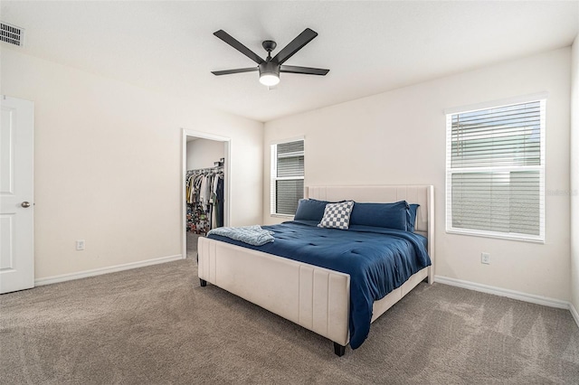 carpeted bedroom with a closet, visible vents, a spacious closet, a ceiling fan, and baseboards