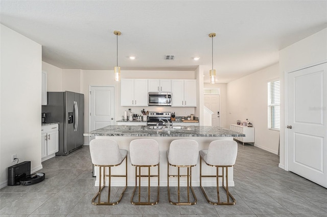 kitchen featuring stainless steel appliances, white cabinetry, a sink, and a kitchen bar