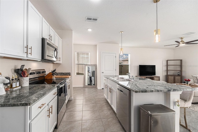 kitchen featuring light tile patterned floors, stainless steel appliances, a sink, visible vents, and open floor plan