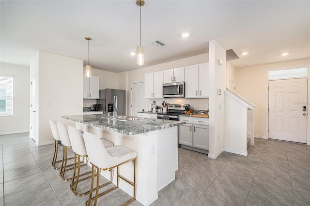 kitchen with light stone counters, a breakfast bar, visible vents, appliances with stainless steel finishes, and a sink