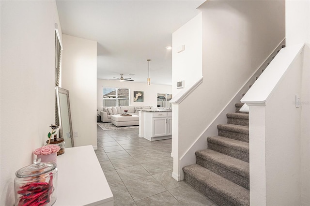 stairway featuring ceiling fan, tile patterned flooring, and baseboards