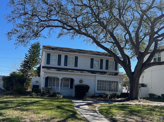 traditional-style house featuring brick siding and a front lawn