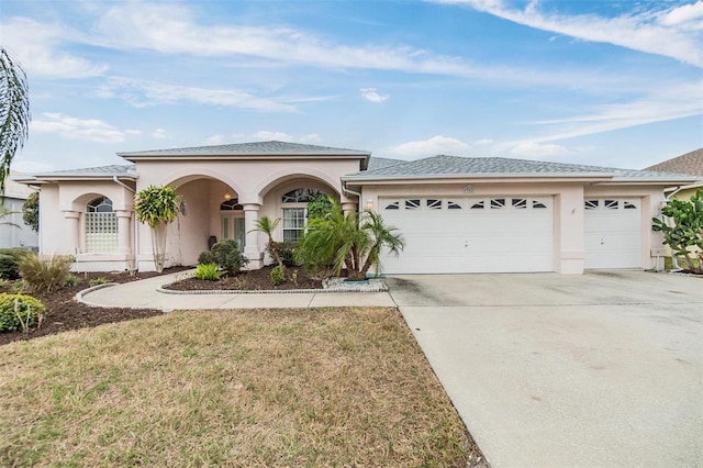 view of front of house featuring a garage, driveway, a front yard, and stucco siding