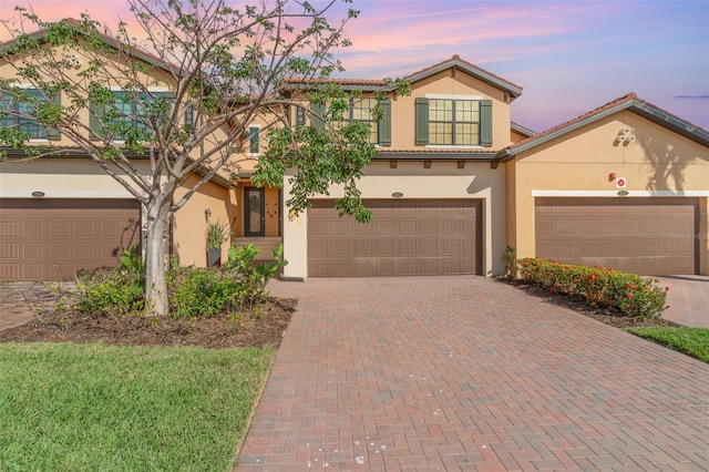 view of front of home with a tile roof, decorative driveway, and stucco siding