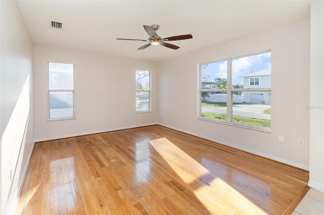 spare room with light wood-type flooring, visible vents, baseboards, and a ceiling fan