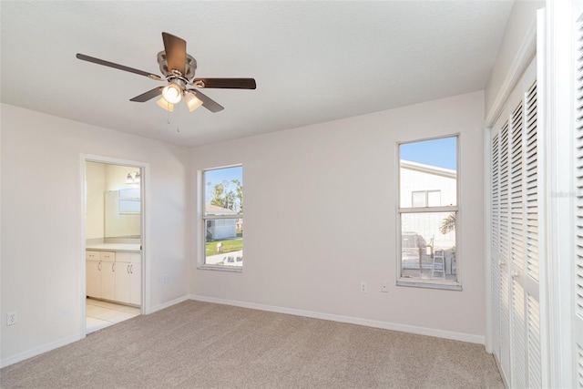 unfurnished bedroom featuring light carpet, multiple windows, baseboards, and a closet