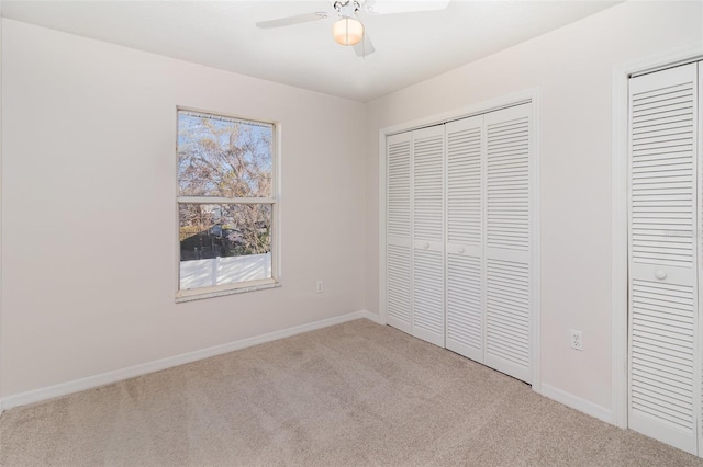 unfurnished bedroom with a ceiling fan, baseboards, two closets, and carpet flooring