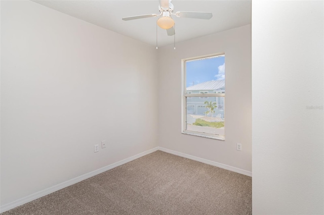 spare room with light carpet, a ceiling fan, and baseboards