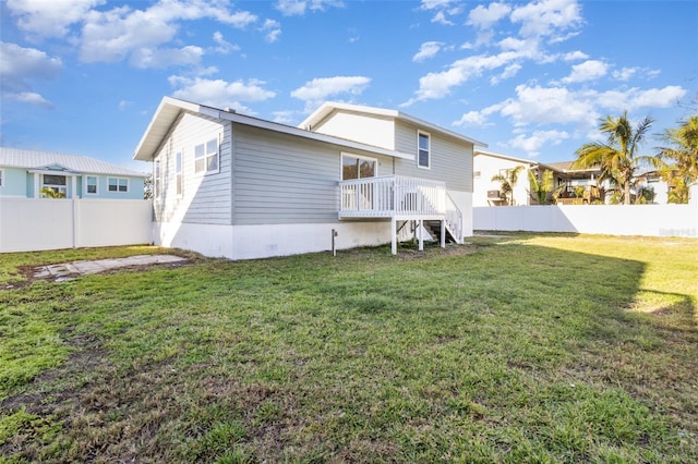 rear view of house featuring a lawn and fence