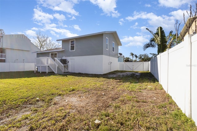 back of house with a yard, a fenced backyard, and a gate