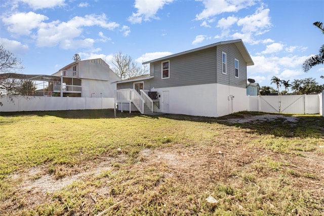 back of house with a gate, fence, and a yard