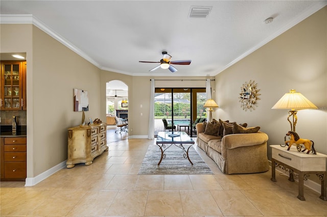 living area with ornamental molding, arched walkways, visible vents, and ceiling fan