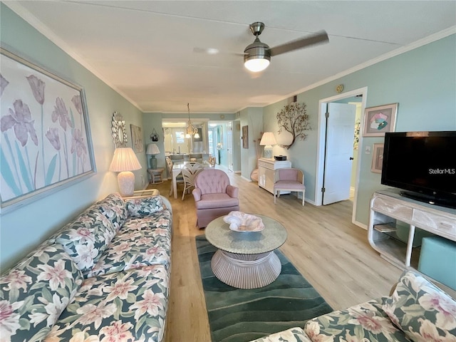 living area with light wood-type flooring, a ceiling fan, baseboards, and crown molding