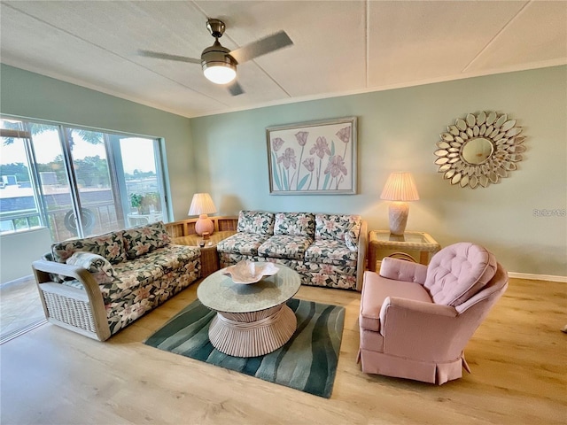 living area featuring ornamental molding, wood finished floors, and a ceiling fan