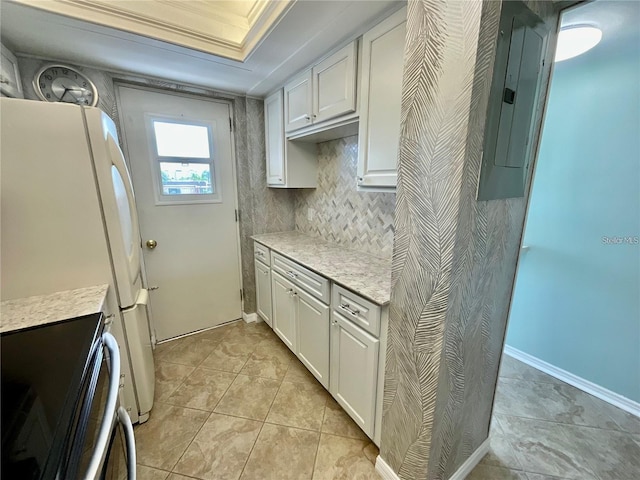 kitchen featuring electric range, white cabinetry, backsplash, and freestanding refrigerator