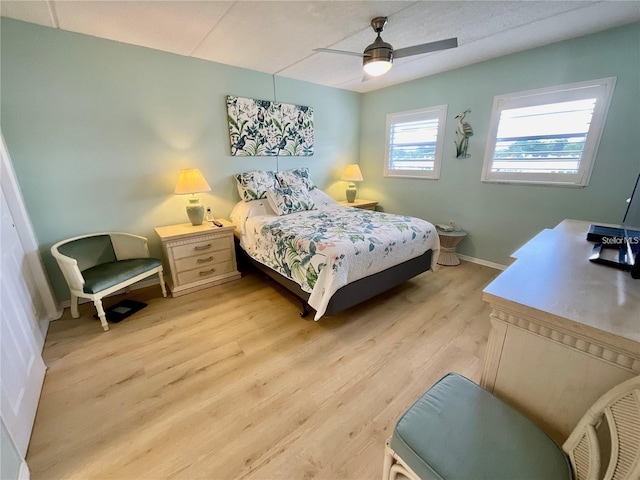 bedroom featuring a ceiling fan, baseboards, and light wood finished floors