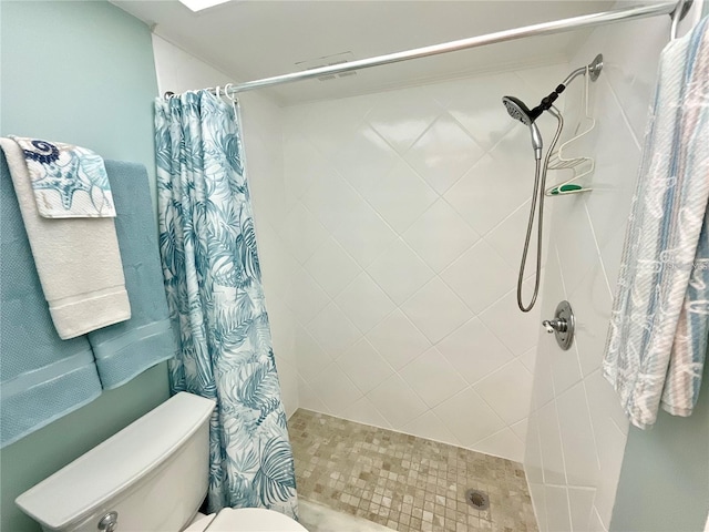 bathroom featuring tiled shower and toilet