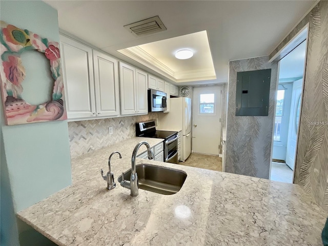 kitchen featuring stainless steel appliances, a sink, visible vents, electric panel, and a tray ceiling