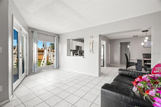 living room with a textured ceiling, light tile patterned flooring, and baseboards