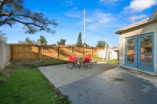 view of patio featuring french doors, outdoor dining space, and a fenced backyard