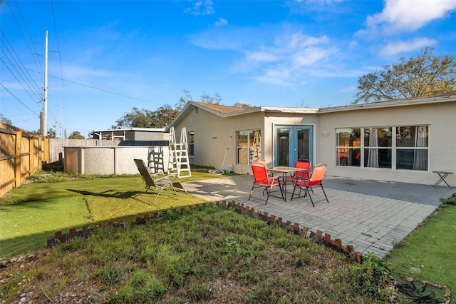 back of property featuring french doors, a patio, stucco siding, a lawn, and a fenced backyard