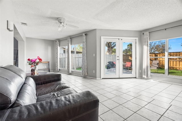 living room with light tile patterned floors, a textured ceiling, visible vents, a ceiling fan, and french doors