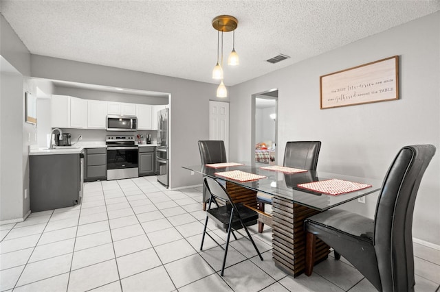 dining room with a textured ceiling, light tile patterned flooring, visible vents, and baseboards